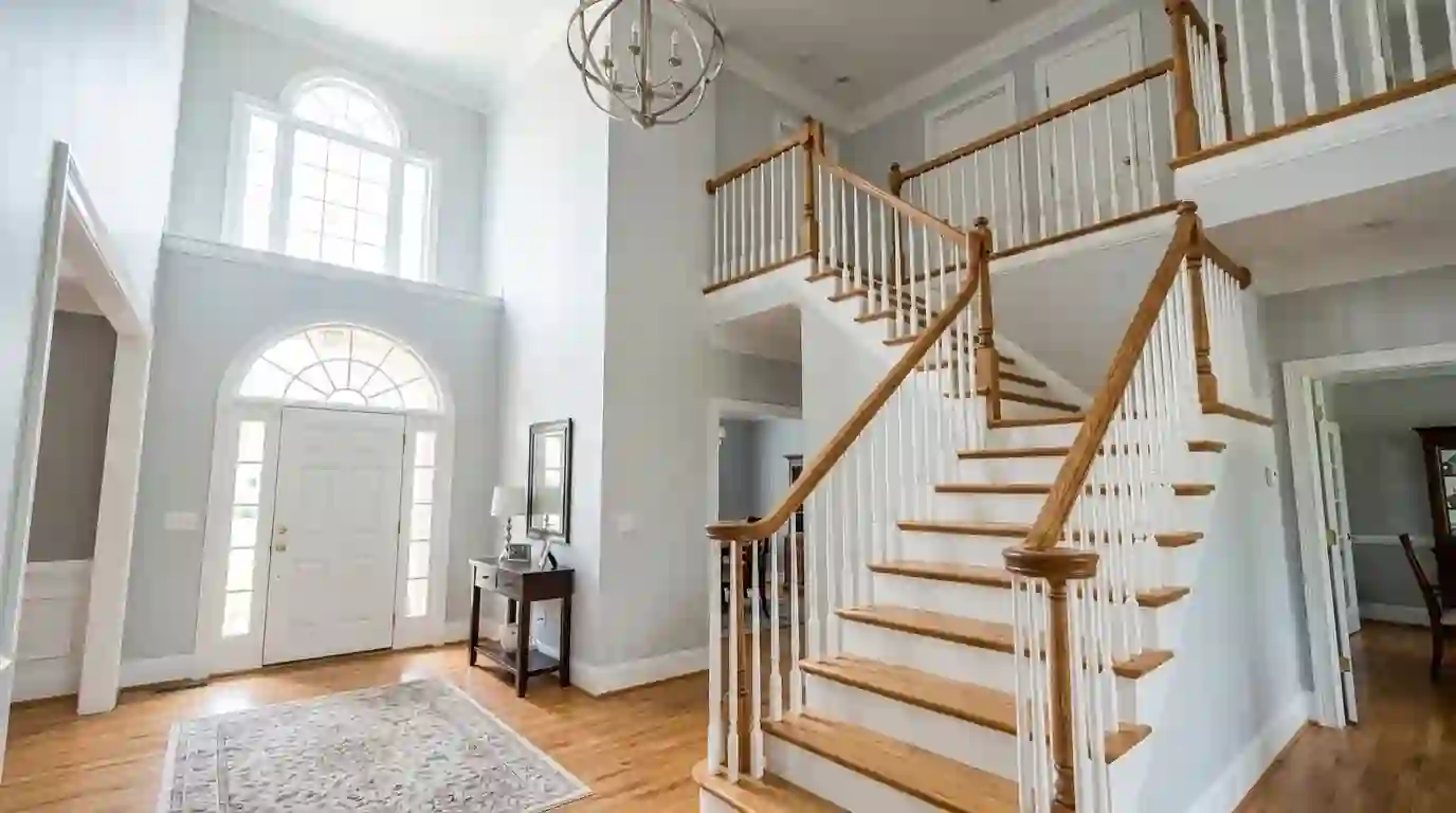 Two-story foyer with fresh gray walls and oak handrail in Duluth