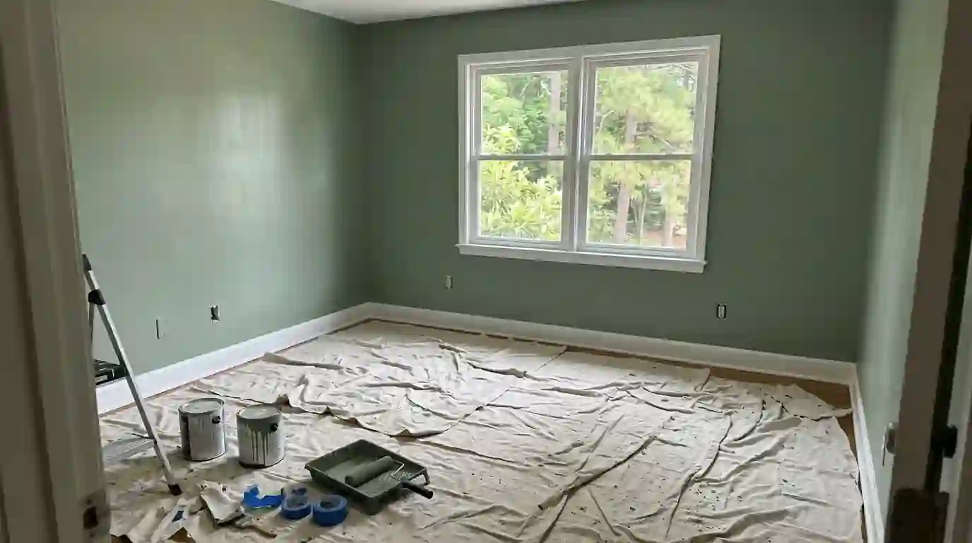 Freshly painted sage green bedroom with drop cloths on the floor